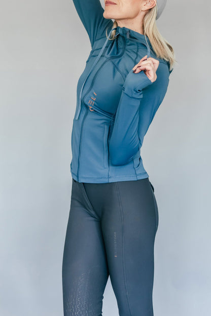 Person wearing a blue jacket and dark gray breeches against a light gray background