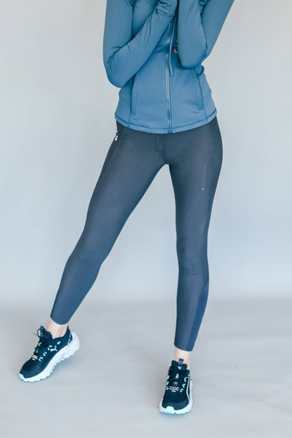 Person wearing a blue jacket and gray breeches on a plain background