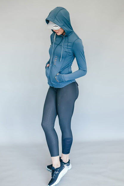 Person wearing a blue and grey athletic outfit with a hood on a plain background
