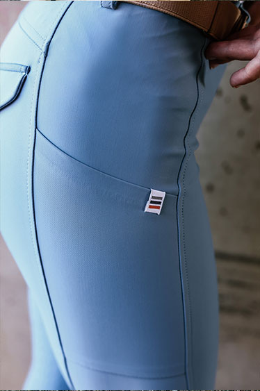 Light blue riding pants with a brand logo on a blurred background