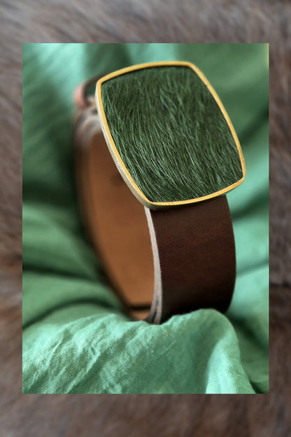 Close-up of a brown belt with green textured top on a green fabric background