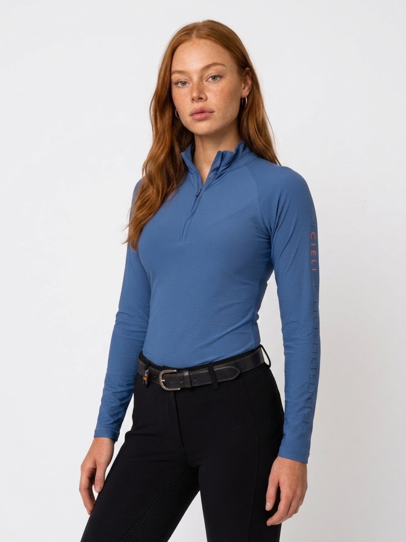 The Faye Baselayer in blue with a quarter-zip collar and long sleeves.