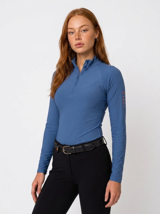 The Faye Baselayer in blue with a quarter-zip collar and long sleeves.