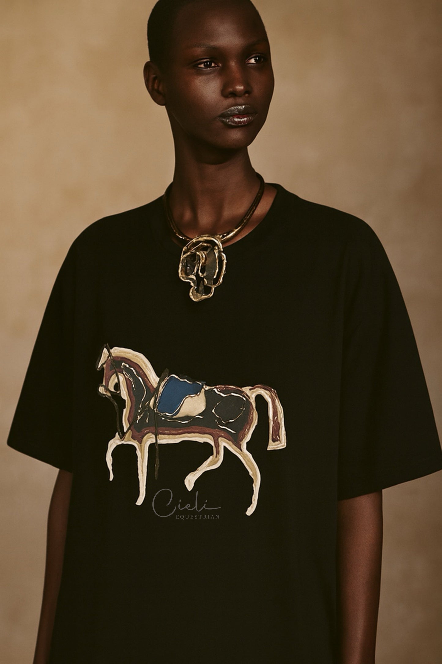 Person wearing a black t-shirt with a horse design on a beige background
